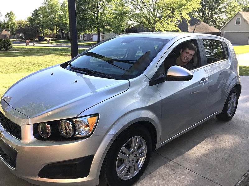 Man smiling from the window of his new car