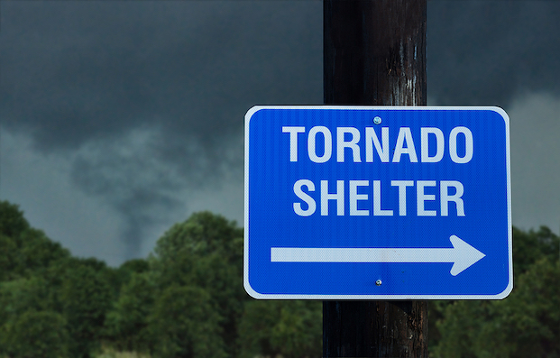 Tornado Shelter directional street sign with backdrop of dark and cloudy skies
